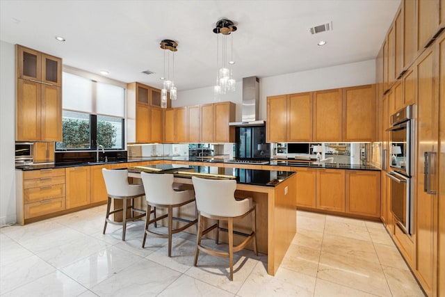 kitchen featuring sink, a kitchen bar, hanging light fixtures, a center island, and wall chimney range hood