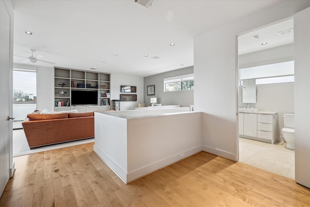 kitchen featuring sink, kitchen peninsula, built in features, ceiling fan, and light hardwood / wood-style floors