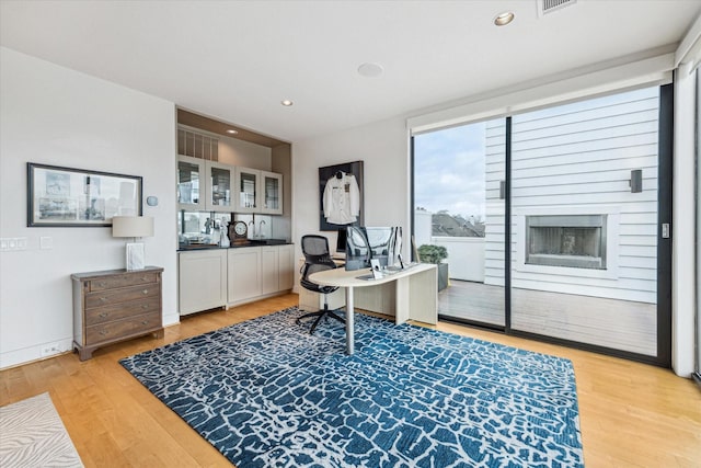 office with a fireplace and light hardwood / wood-style flooring