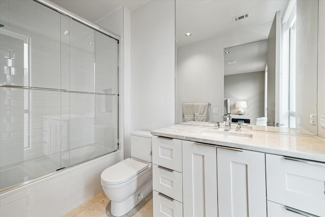 full bathroom featuring vanity, toilet, and bath / shower combo with glass door