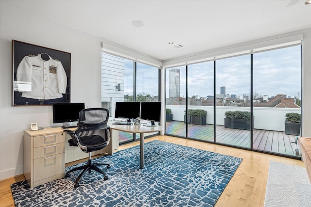 home office with a wall of windows and hardwood / wood-style floors