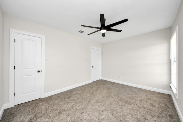 spare room with carpet, visible vents, baseboards, and a ceiling fan