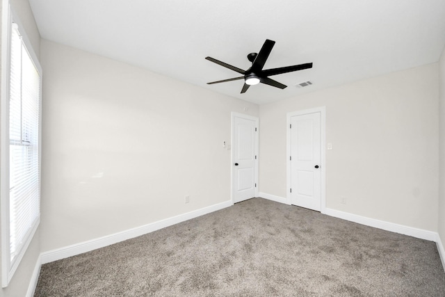 carpeted spare room featuring ceiling fan, visible vents, and baseboards