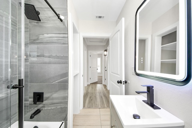 full bath featuring a shower with door, tile patterned flooring, visible vents, and vanity