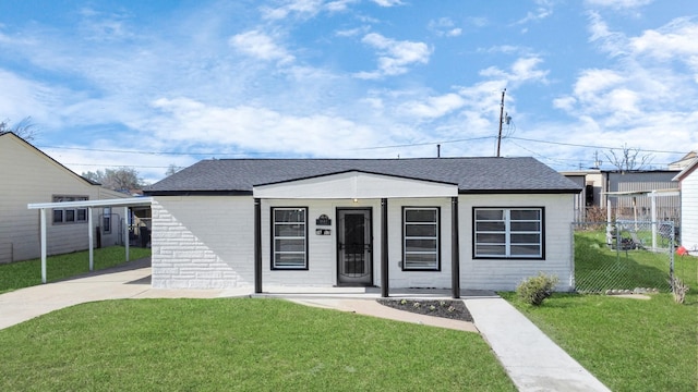 bungalow featuring a carport, a front yard, roof with shingles, and fence