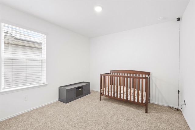 bedroom with a crib and light colored carpet