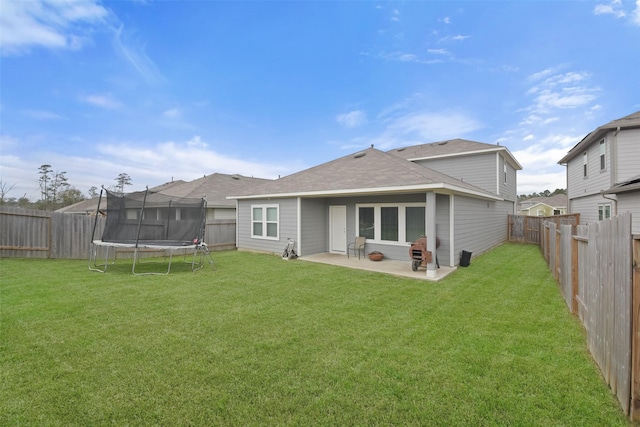 rear view of house with a yard, a trampoline, and a patio area