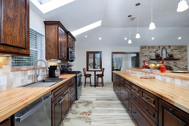 kitchen with pendant lighting, sink, wooden counters, and appliances with stainless steel finishes