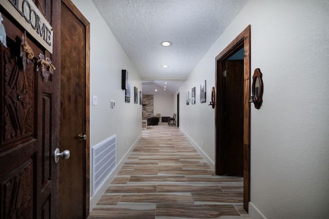 hall featuring light hardwood / wood-style flooring and a textured ceiling