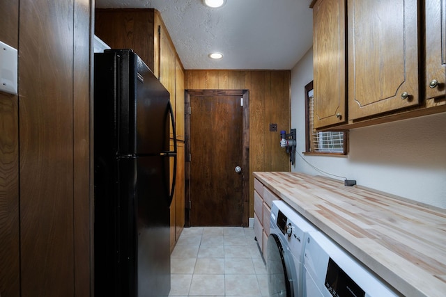 kitchen featuring washer / clothes dryer, light tile patterned flooring, wooden counters, and black fridge