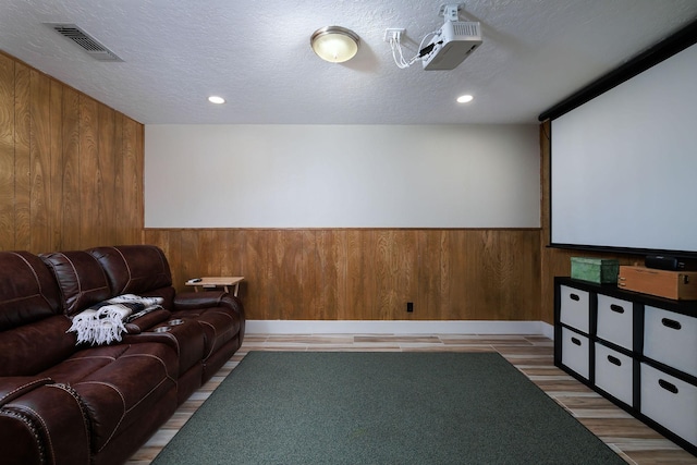 home theater room with hardwood / wood-style floors, a textured ceiling, and wood walls