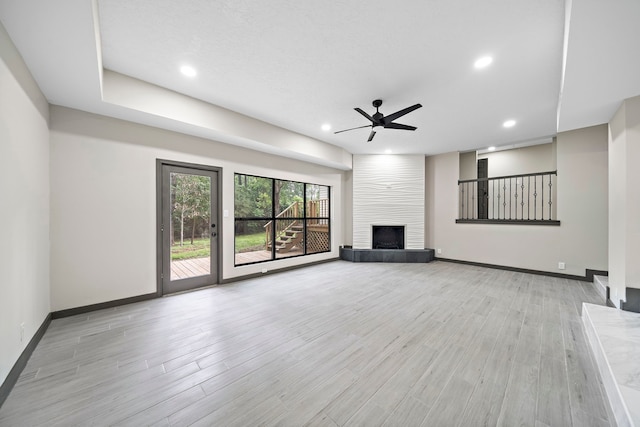 unfurnished living room featuring ceiling fan, a fireplace, and light hardwood / wood-style flooring