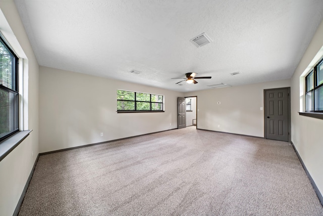 carpeted empty room with ceiling fan and a textured ceiling