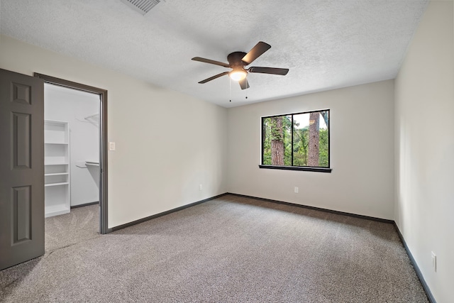 carpeted empty room with ceiling fan and a textured ceiling