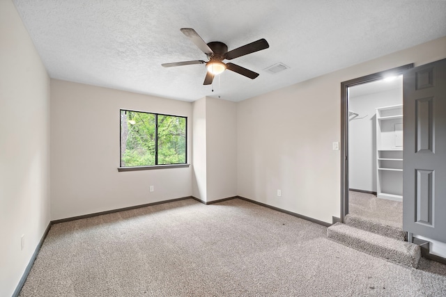 carpeted empty room with ceiling fan and a textured ceiling