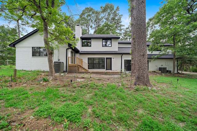 rear view of house with a yard and central AC