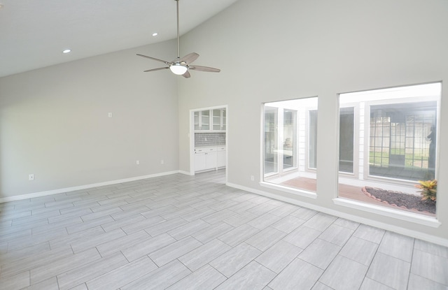 empty room featuring high vaulted ceiling, recessed lighting, a ceiling fan, and baseboards