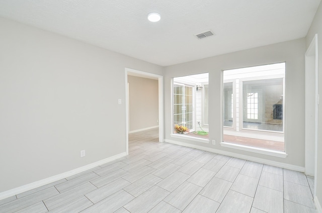 unfurnished room with baseboards and visible vents