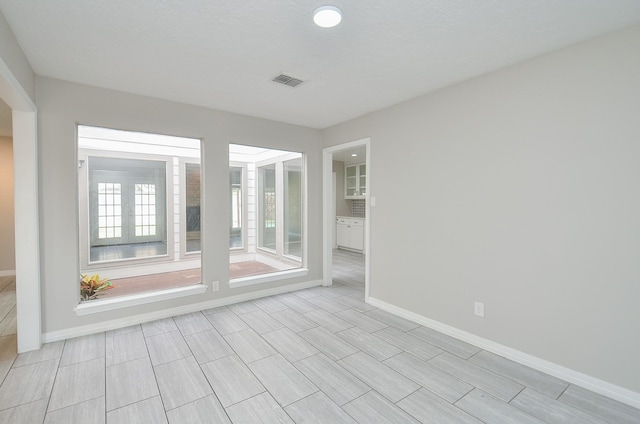 unfurnished room with baseboards and visible vents