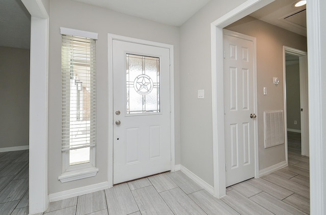 foyer with plenty of natural light, visible vents, baseboards, and wood finish floors