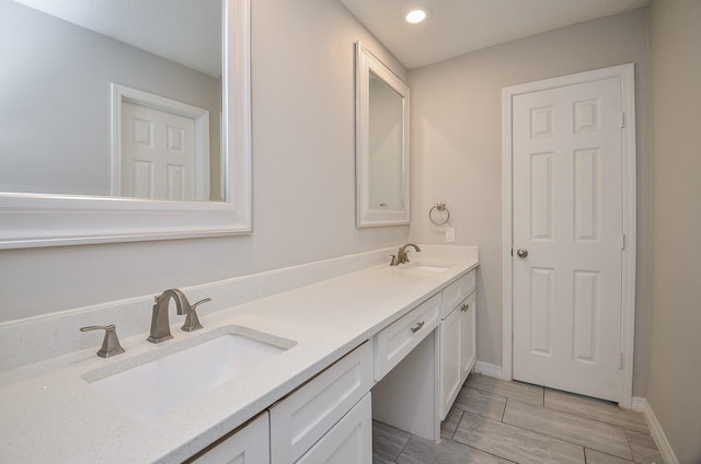 bathroom with double vanity, baseboards, and a sink