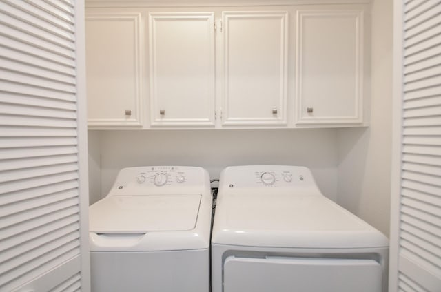 clothes washing area featuring cabinet space and washer and clothes dryer