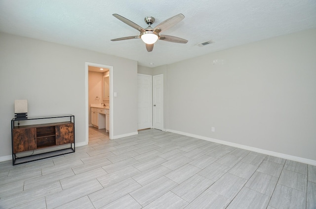 unfurnished bedroom featuring a ceiling fan, baseboards, visible vents, and a textured ceiling