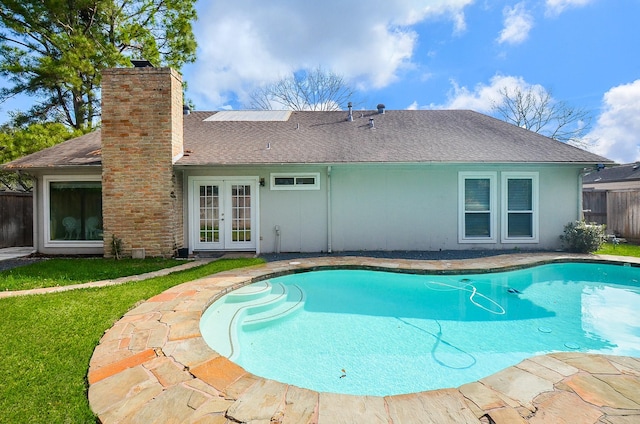 outdoor pool with a yard, french doors, and fence