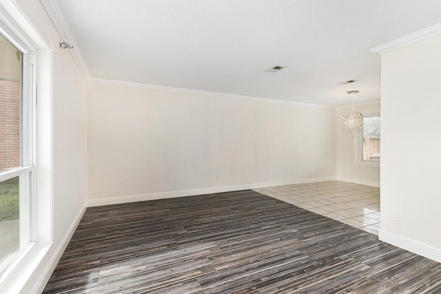 empty room featuring crown molding, dark hardwood / wood-style floors, and an inviting chandelier