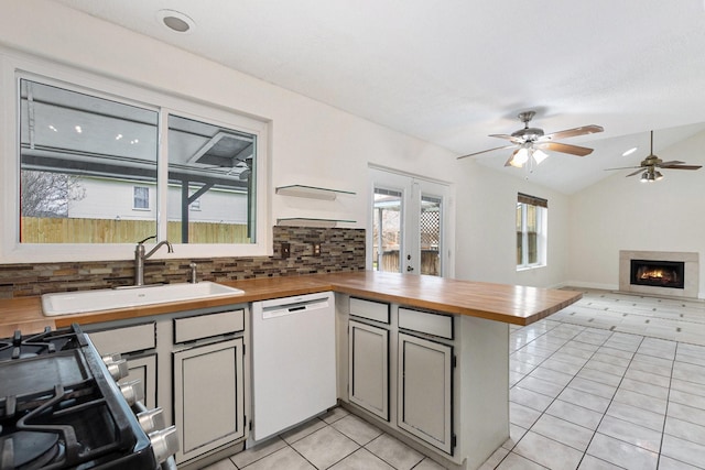 kitchen featuring light tile patterned flooring, sink, white dishwasher, kitchen peninsula, and decorative backsplash