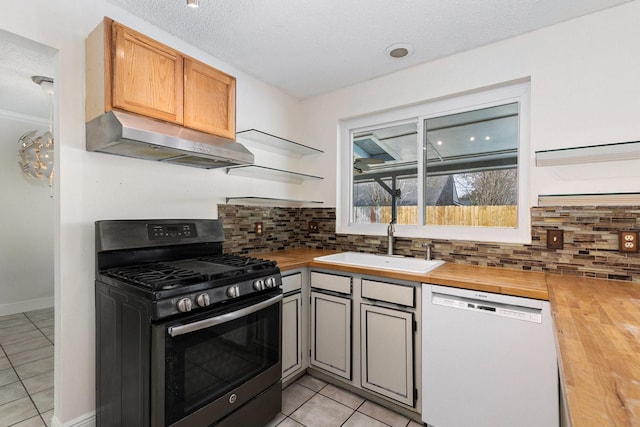 kitchen featuring butcher block countertops, tasteful backsplash, sink, white dishwasher, and stainless steel gas range