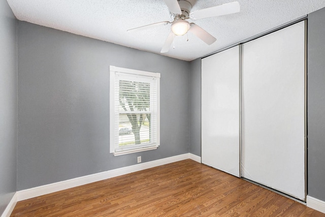 unfurnished bedroom with ceiling fan, hardwood / wood-style floors, a textured ceiling, and a closet