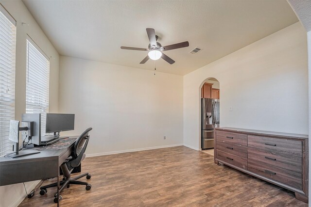 home office with arched walkways, visible vents, baseboards, and wood finished floors