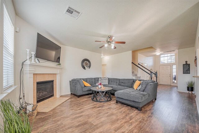 living room with visible vents, a tile fireplace, stairway, and wood finished floors