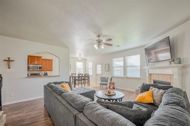 living room featuring visible vents, a fireplace, baseboards, and wood finished floors