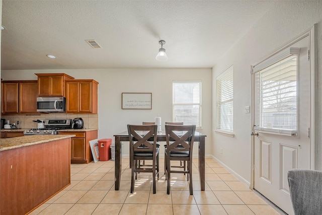 dining space with light tile patterned floors, visible vents, baseboards, and a textured ceiling