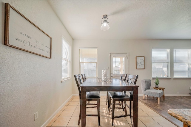 dining room with light tile patterned floors, a textured ceiling, and baseboards