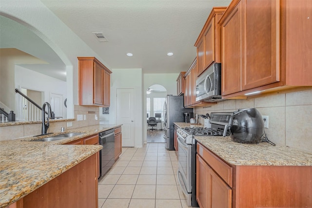 kitchen with light tile patterned floors, brown cabinetry, visible vents, a sink, and appliances with stainless steel finishes