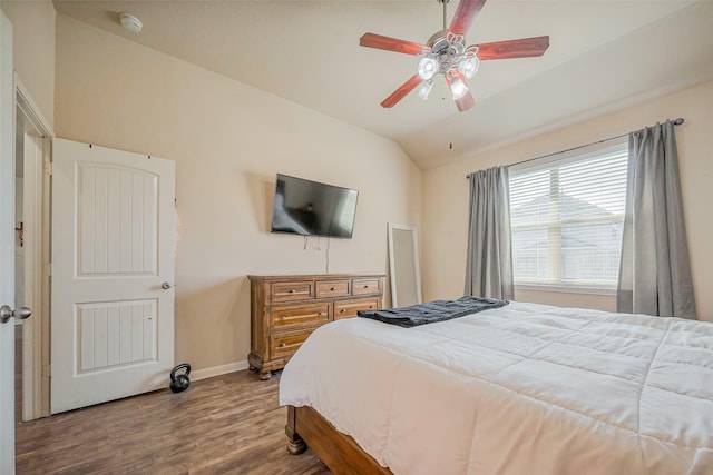 bedroom featuring baseboards, lofted ceiling, wood finished floors, and a ceiling fan