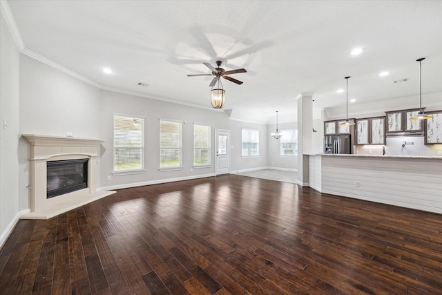 unfurnished living room with dark hardwood / wood-style floors, ornamental molding, a fireplace, and ceiling fan with notable chandelier