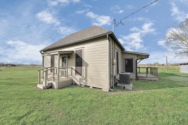 rear view of property featuring central AC, a yard, and a rural view