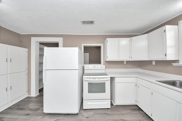 kitchen with white cabinetry, white appliances, and light hardwood / wood-style floors