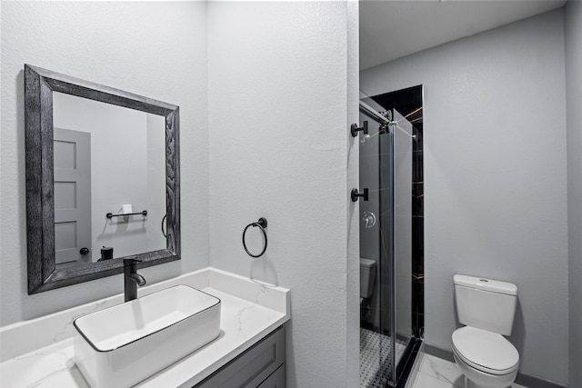 bathroom with vanity, a shower with door, and toilet