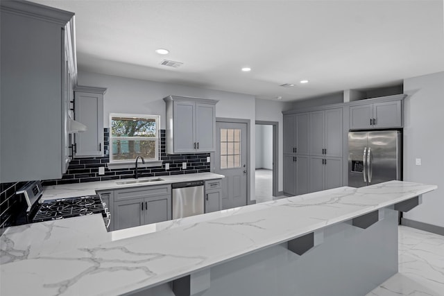 kitchen featuring appliances with stainless steel finishes, a kitchen breakfast bar, sink, and gray cabinetry