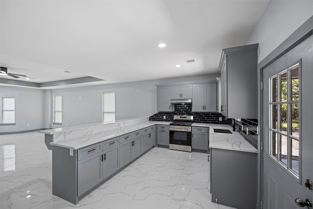 kitchen featuring sink, tasteful backsplash, stainless steel range, gray cabinets, and kitchen peninsula