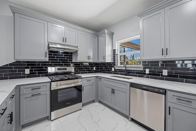 kitchen with sink, light stone counters, gray cabinets, stainless steel appliances, and backsplash