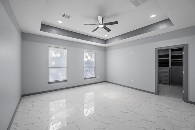 empty room featuring a raised ceiling and ceiling fan