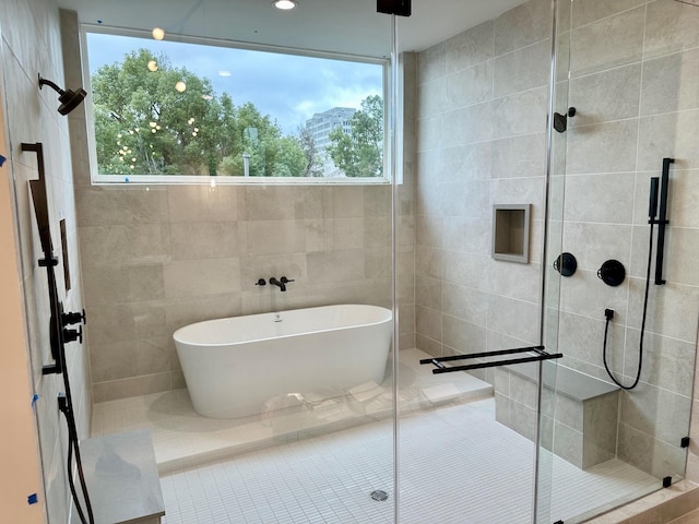 bathroom with tile patterned floors, a healthy amount of sunlight, independent shower and bath, and tile walls