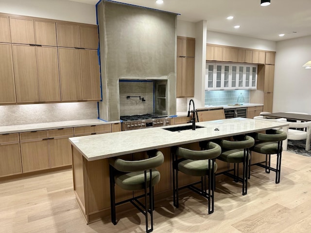 kitchen featuring a breakfast bar area, light hardwood / wood-style floors, sink, and a center island with sink