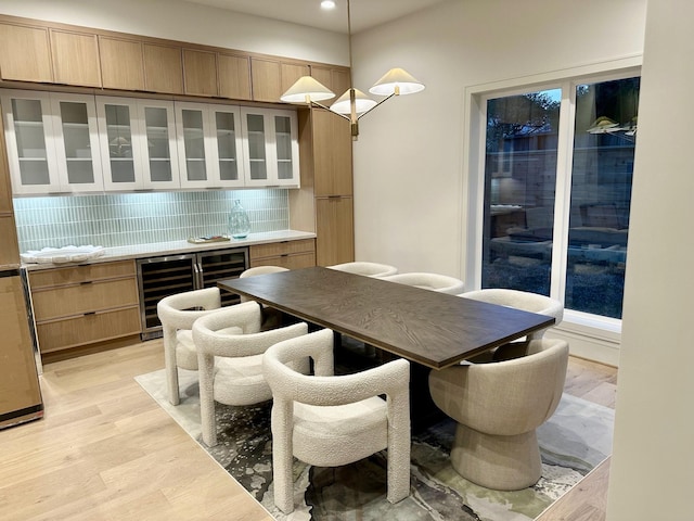 dining space with light hardwood / wood-style floors and beverage cooler